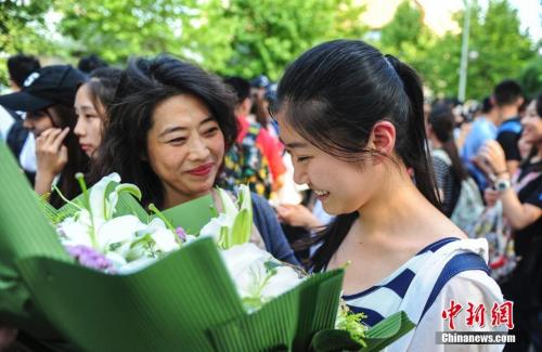 資料圖：山東濟(jì)南眾多考生手捧鮮花在家長的簇?fù)硐職g快告別高考。中新社記者 張勇 攝
