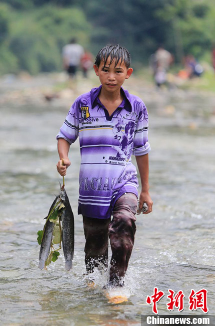 圖為7月9日，一名男孩在鬧魚節(jié)活動中抓到了兩條魚。譚凱興 攝