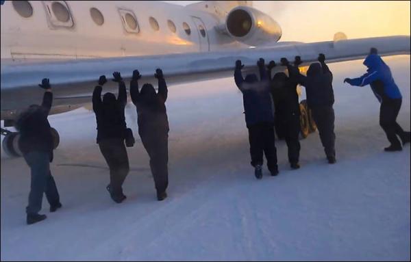 伊加爾市一架客機起飛前被凍在了跑道上。飛機上的乘客不得不下來推飛機。