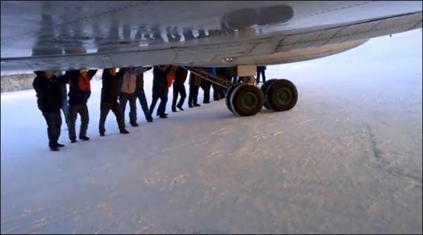 　伊加爾市一架客機起飛前被凍在了跑道上。飛機上的乘客不得不下來推飛機。