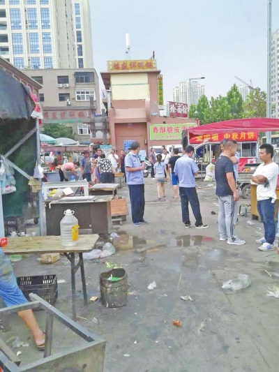 昨天，執(zhí)法人員在京廣路長江路口整治“僵尸圍擋”及圍擋內(nèi)的攤販。
