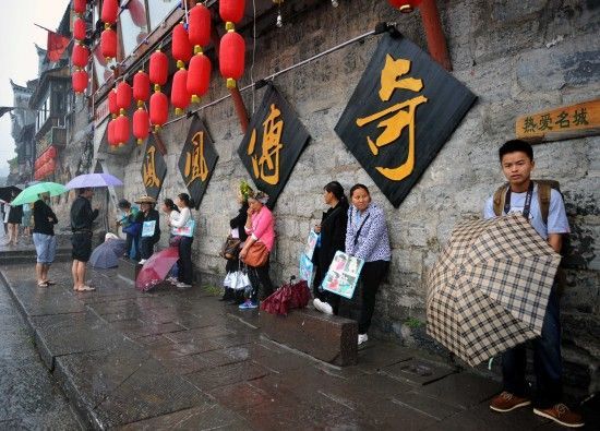 　4月29日上午11時(shí)20分，一些游客和古城當(dāng)?shù)氐木用穸阍谝粋€(gè)酒吧的屋檐下避雨。這些當(dāng)?shù)鼐用褚詾橛慰团恼罩\生，一場(chǎng)降雨讓他們的生意更加清淡。