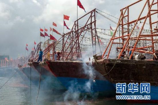 2013年8月1日 南海開漁日 臨高迎新港 8月1日，海南省臨高縣漁民在船上鳴放鞭炮慶祝武蓮港開港。