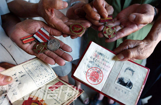 幾位志愿軍老兵展示自己的立功證、傷殘軍人證與勛章