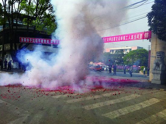 市民在普洱市主干道振興大道的金孔雀交通運(yùn)輸集團(tuán)有限公司門(mén)前燃放鞭炮，公司門(mén)前掛著“貪腐份子沈培平被查處，罪有應(yīng)得，大快人心。”的條幅