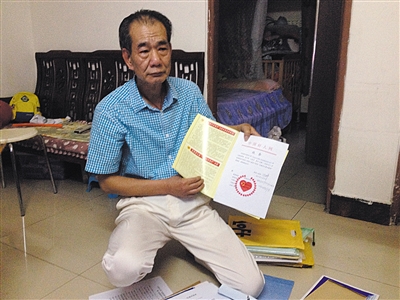 翻出一家網(wǎng)站贈予的“中國好人”證書，區(qū)少坤單膝跪在地上，“你看，我是中國好人啊?！?范春旭 攝