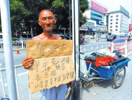 老人舉著牌子在路邊等候失主。京華時(shí)報(bào)記者譚青攝