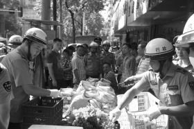 7月11日，瀏陽(yáng)市北正中路，執(zhí)法人員暫扣張海的水果。這是瀏陽(yáng)市城管局拍攝的執(zhí)法現(xiàn)場(chǎng)圖。