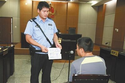昨日庭審中，法警向趙某出示其扎完車胎后所留辱罵公司的紙條。通訊員 李秀文 攝