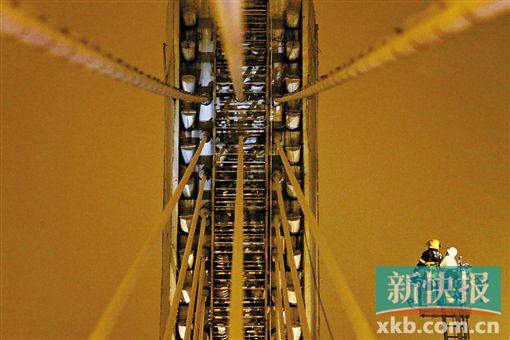 截至今日零時(shí)，男子仍未有下橋舉動(dòng)。圖為公安和消防人員乘消防云梯在高空上和男子交談。