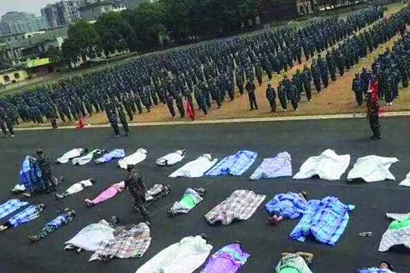 20多名女生躺在瀝青跑道上，身上嚴(yán)嚴(yán)實實地裹著棉被，接受太陽的照曬。