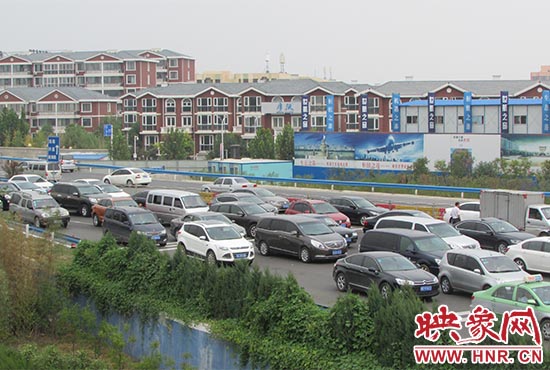 記者看到鄭州機(jī)場(chǎng)收費(fèi)站口車(chē)輛排隊(duì)，與此形成鮮明對(duì)比的是，路的對(duì)面（另一半幅）卻車(chē)輛較少，通行順暢。