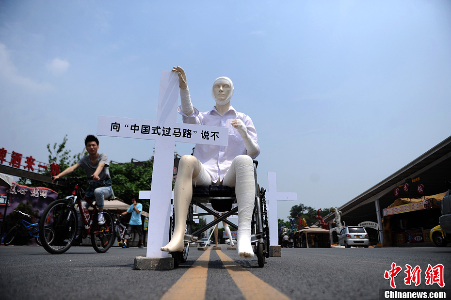 4月16日，重慶市洋人街上擺放著兩個受了傷的塑料人像“模特”，旁邊十字架上寫著向“中國式過馬路”說不