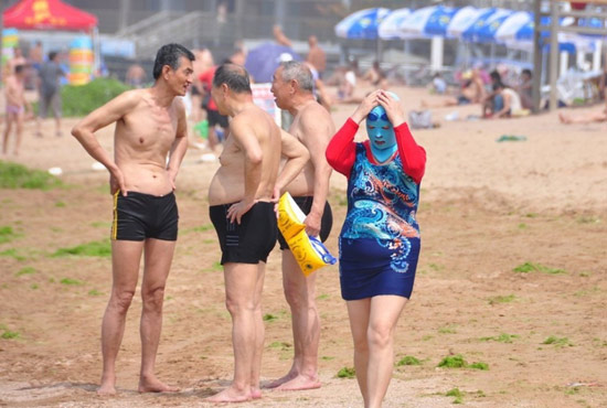 2013年7月3日，山東青島青島高溫來襲，“青島大媽”不懼滸苔，戴著“強(qiáng)盜面具”出現(xiàn)在海水浴場消暑降