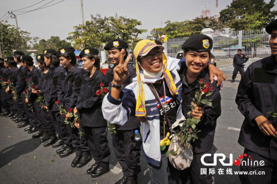 2013年12月03日,曼谷總理府與曼谷警署允許反政府示威民眾進入,雙方進入暫時“停戰(zhàn)”狀態(tài)迎接泰王生日。曼谷警察總署,女警們手持鮮花送給反政府示威民眾。圖片來源:Manish Swarup/東方IC