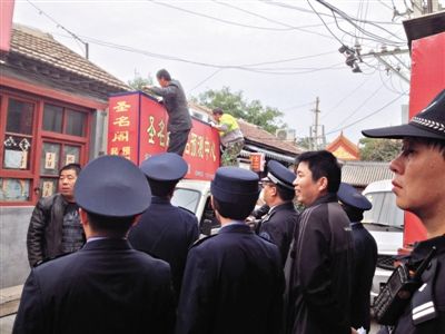 昨日下午,東城區(qū)工商、城管、公安等部門,對雍和宮附近的預(yù)測中心進行清理整頓,站在車頂?shù)膬擅と苏鸪患摇邦A(yù)測中心”的招牌。因雍和宮、白云觀等文化景點外聚集大量算命先生,被媒體稱為“算命一條街”。本版攝影/新京報記者 李寧 攝