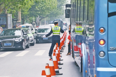 省人民醫(yī)院南門的路中間擺放反光錐，交警示意由西向東車輛從前方繞行。