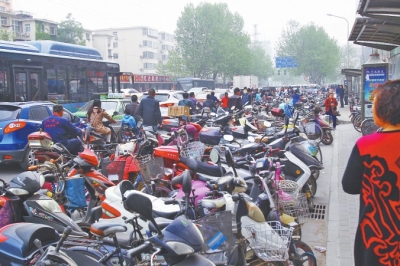 省人民醫(yī)院北門，路邊的公交站牌處停滿非機動車，上、下客只能在快車道上。