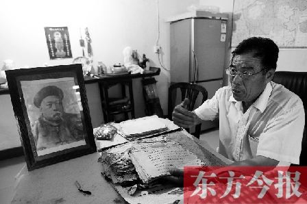 　魏樹紹手拿《物權法講義》手稿，在講訴先祖書寫“物權法”的歷史（相框里就是魏聯(lián)奎）