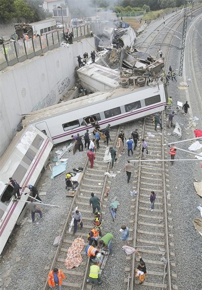24日，救援人員在西班牙列車脫軌現(xiàn)場。一節(jié)車廂被強大的慣性拋上鐵道邊的高臺。
