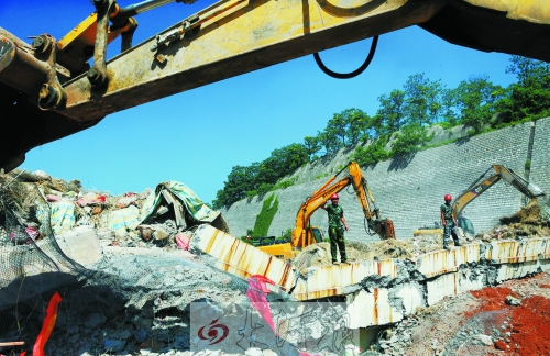 為確保道路盡早通車，工人師傅冒著烈日，指揮施工機械清理爆破現(xiàn)場