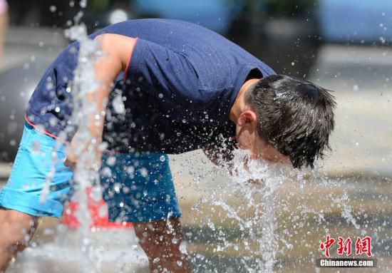 5月29日，一名小孩將頭伸向北京街頭的噴泉以降溫祛暑。