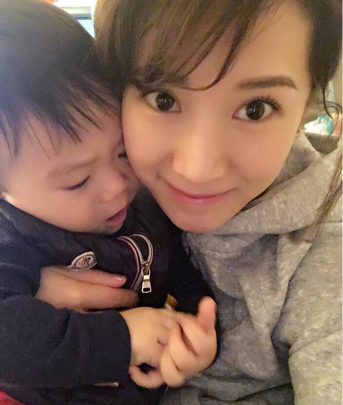 照片中李念狂吻兒子，小寶貝自顧自地玩著。