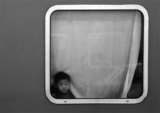 一個孩子把頭伸向窗外，他想再看送別的親人一眼