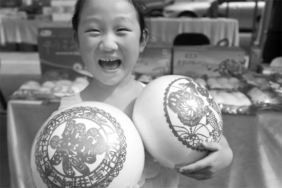 在2013河南食品安全宣傳周活動(dòng)現(xiàn)場(chǎng)，一個(gè)小女孩抱著參展的特色大饅頭樂(lè)開(kāi)了花