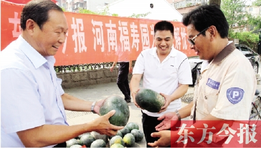 河南福壽園區(qū)域總經(jīng)理吳正宗（左一）、東方今報發(fā)行中心副總監(jiān)王路喜（中）在街頭給市民送瓜