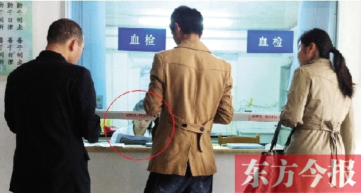 昨日，鄭州市二七區(qū)疾控中心辦證大廳，血檢窗口內(nèi)一名女工作人員，邊接受辦證者咨詢邊看報(bào)紙