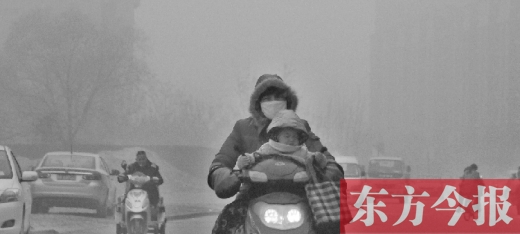 12月8日，鄭州市未來(lái)路上，一位市民帶著孩子在霧中騎行