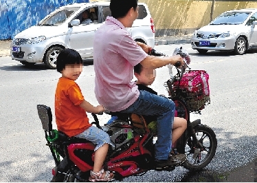 周先生騎著一輛低矮的電動(dòng)車(chē)帶著一對(duì)兒女，很不安全。