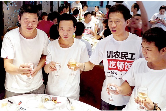活動發(fā)起人張楠（右二）給農民工敬酒。