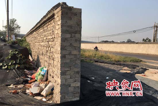 一墻之隔，一邊是道路，一邊是垃圾和荒草，市民質(zhì)疑其為遮羞墻。
