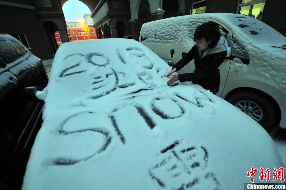 11月18日，行人在車(chē)輛的積雪上涂鴉。