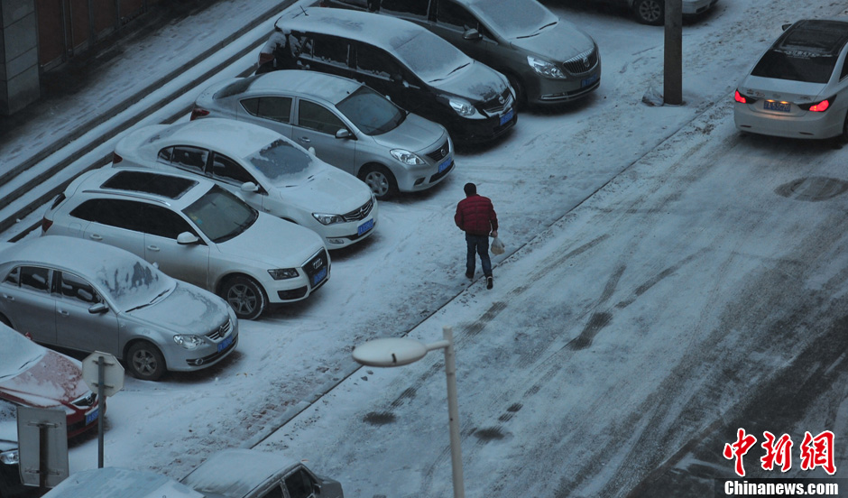 11月18日，行人在沈陽(yáng)街頭的積雪中穿行。