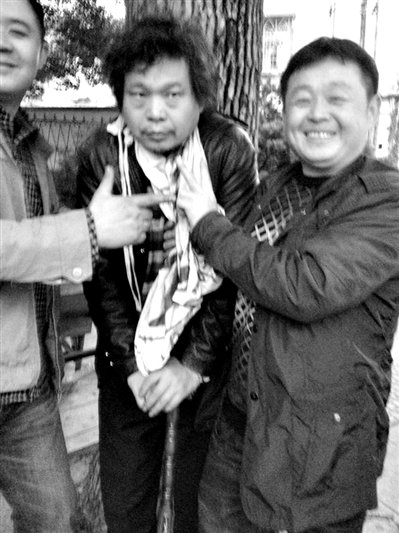 兩名接訪人員與患有癌癥的訪民段新德合影時，面帶笑容擺出勝利的手勢。
