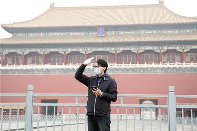 11月1日，北京大部分地區(qū)重度污染，一名游客戴著口罩在午門前揮手跟朋友打招呼。 實習(xí)生 王飛 攝