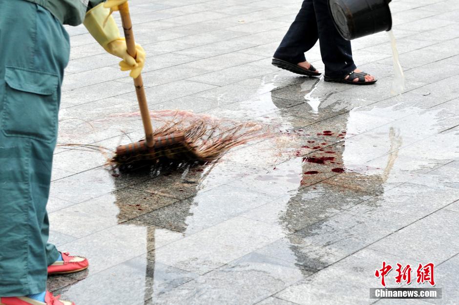 圖為環(huán)衛(wèi)工人在清理案發(fā)地點的血跡。