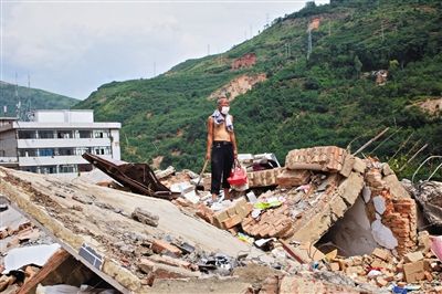 8月9日,龍頭山鎮(zhèn),一位老者在自家房屋廢墟上尋找家當(dāng)。