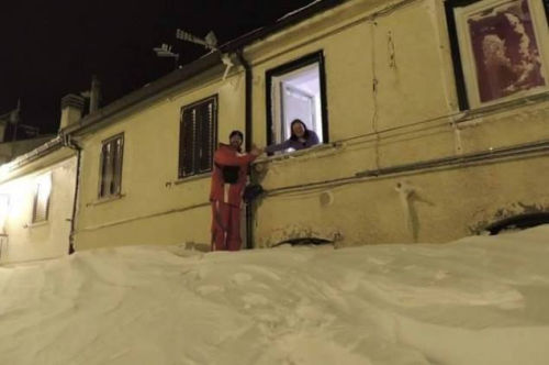 一個(gè)居民站在積雪上，可以與一名二樓鄰居在窗口握手。（來源：意大利氣象局）