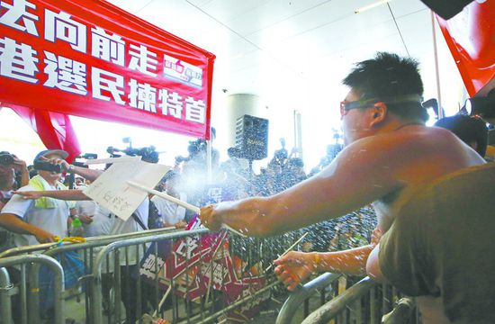 17日，在香港立法會(huì)外，一名反對(duì)政改的男子向支持派人群投擲標(biāo)牌。