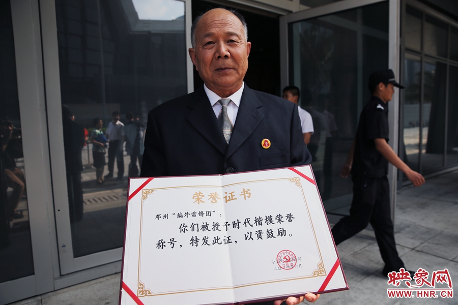 河南鄧州“編外雷鋒團”團長宋清梅向眾多記者展示中宣部授予的“時代楷模”榮譽證書。