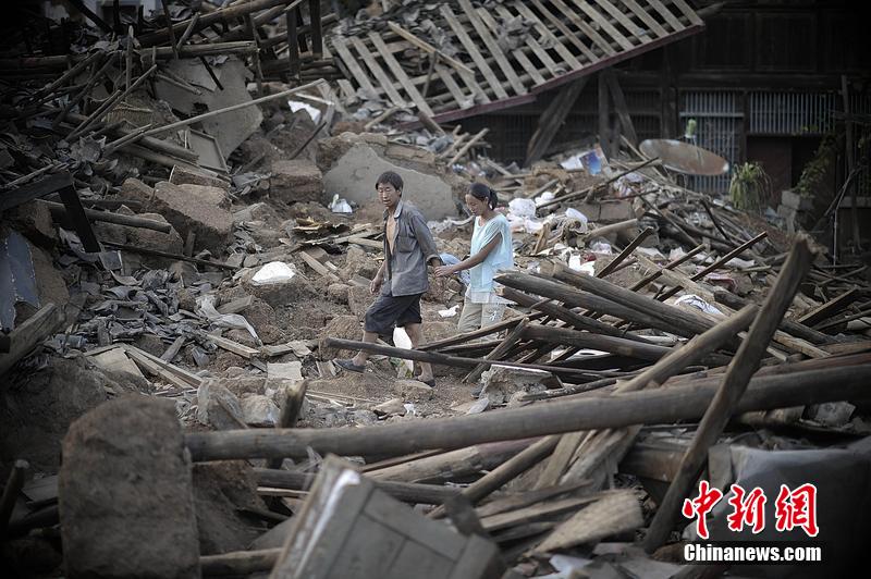 2014年8月5日，云南昭通龍頭山鎮(zhèn)老街，一對夫妻從居住房屋的廢墟中走過。