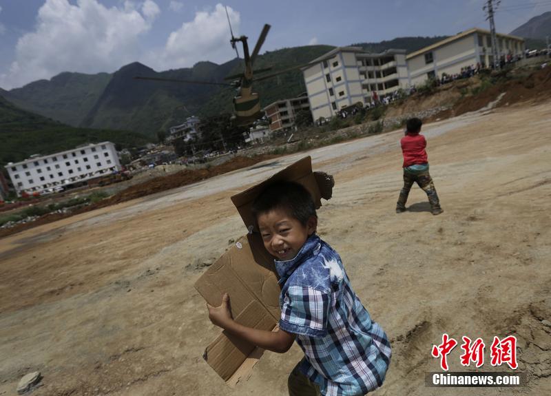 云南省昭通市魯?shù)榭h發(fā)生6.5級地震。幾個孩子在直升機降落的平地上玩耍。