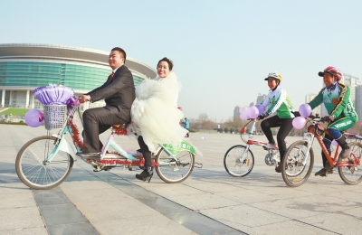 氣球和鮮花裝點(diǎn)的雙人自行車，新郎郝幸福載著美麗新娘回家。
