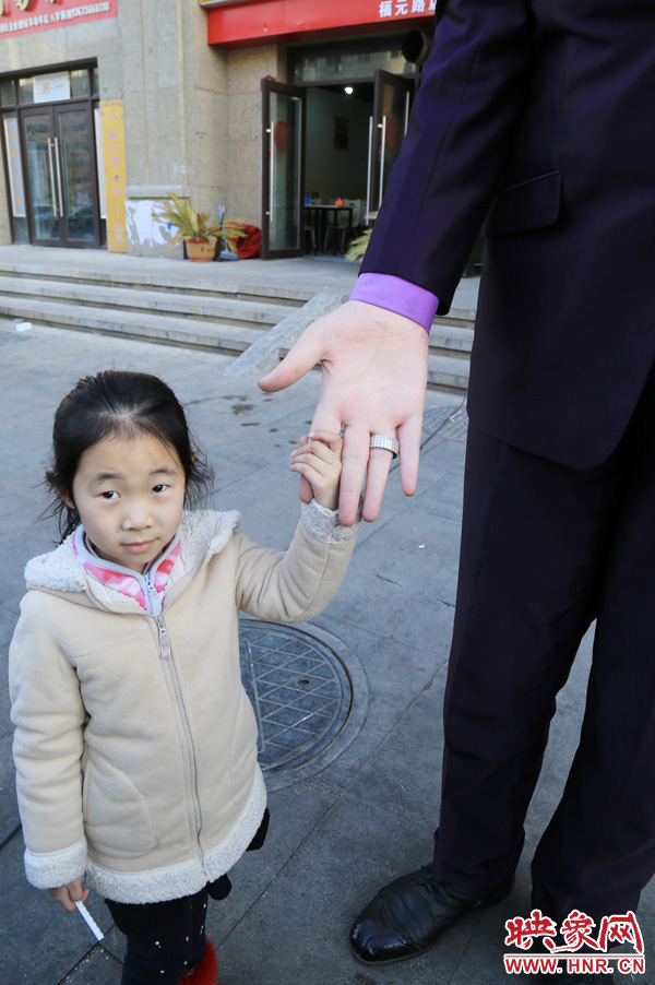 巨人“張歡”牽著一名漂亮的小女孩，兩人的手大小對比非常明顯。
