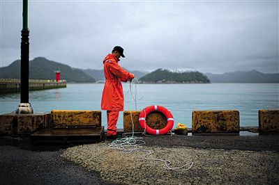 7月6日，韓國珍島，一名海岸警察在港口系救生圈。4月，客輪在珍島近海發(fā)生沉船事故后，仍有11人下落不明。