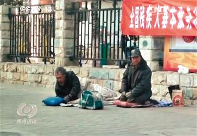 工人體育場北路，兩位乞討者路邊乞討，并輪流扮成“病人”（躺地者）。 央視截圖